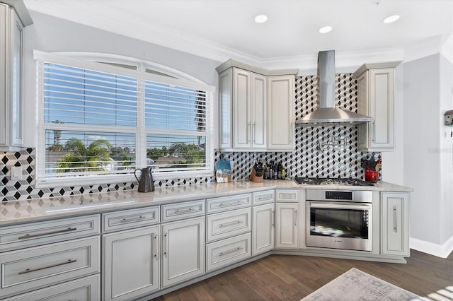 kitchen featuring ornamental molding, appliances with stainless steel finishes, dark hardwood / wood-style floors, and wall chimney range hood