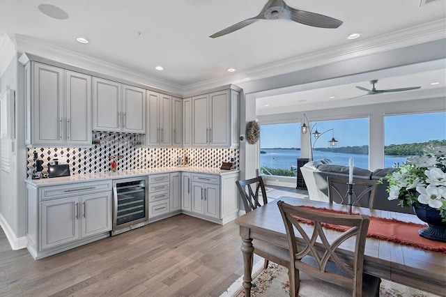 kitchen featuring crown molding, gray cabinets, light hardwood / wood-style flooring, a water view, and wine cooler