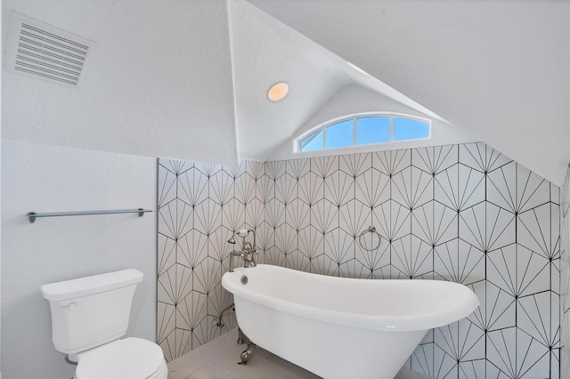 bathroom featuring toilet, vaulted ceiling, tile walls, and a washtub