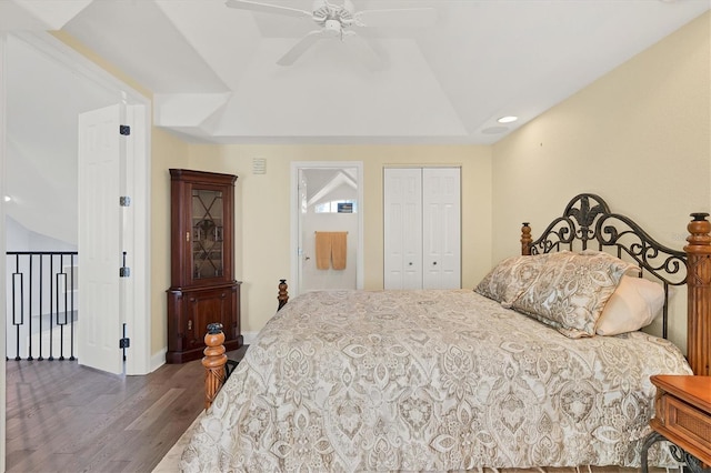 bedroom with lofted ceiling, dark hardwood / wood-style floors, a tray ceiling, a closet, and ceiling fan