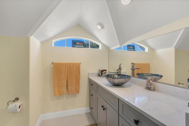 bathroom with vaulted ceiling, vanity, and a textured ceiling