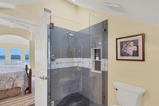 bathroom with hardwood / wood-style flooring, vaulted ceiling, a shower with shower door, and toilet