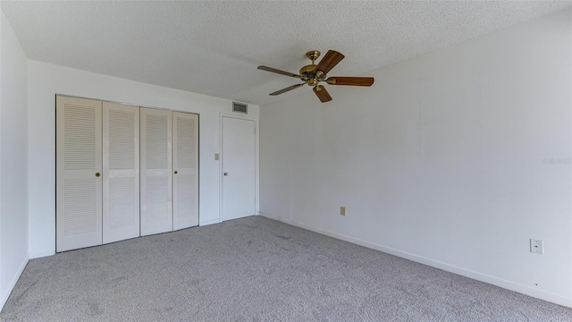 unfurnished bedroom with ceiling fan, light colored carpet, a textured ceiling, and a closet