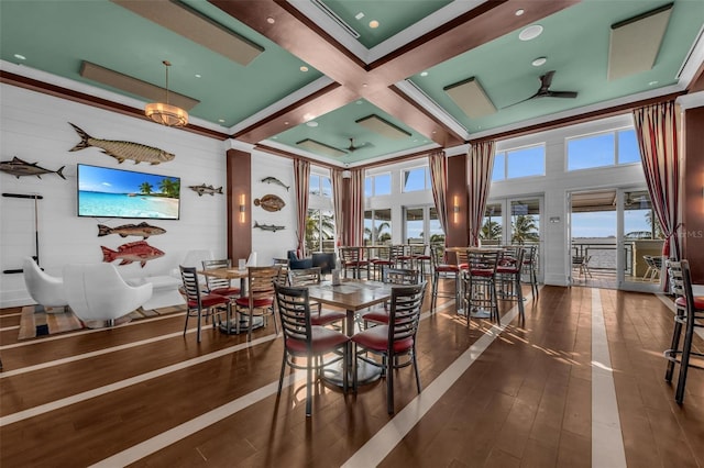 dining space with ceiling fan, dark wood-type flooring, a high ceiling, and coffered ceiling