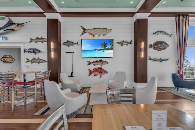 living room with hardwood / wood-style flooring, wood walls, and beamed ceiling