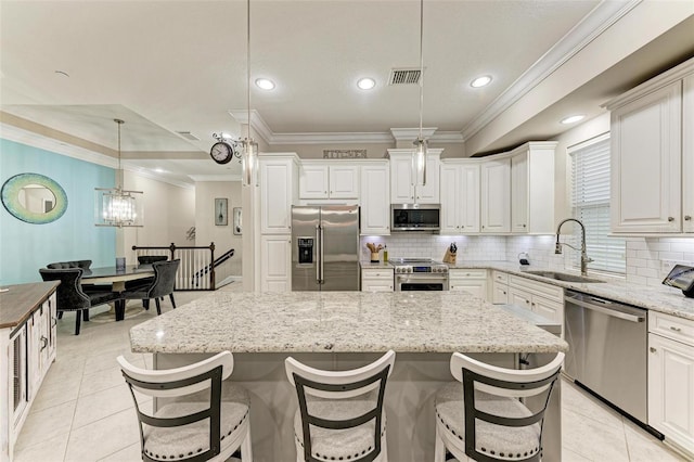 kitchen featuring high end appliances, decorative light fixtures, a kitchen island, and sink