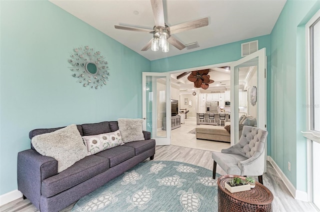 living room featuring light wood-type flooring, french doors, and ceiling fan