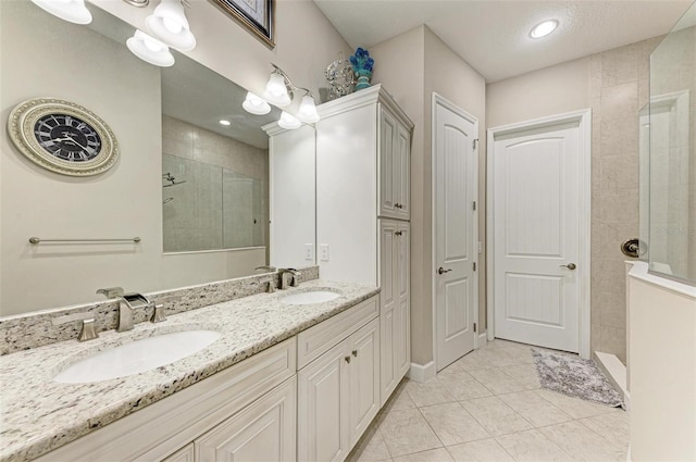 bathroom featuring vanity, tile patterned flooring, and a tile shower