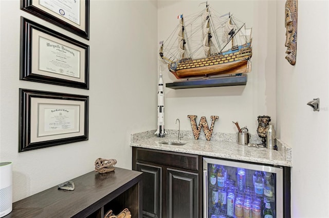 bar featuring light stone countertops, sink, and wine cooler