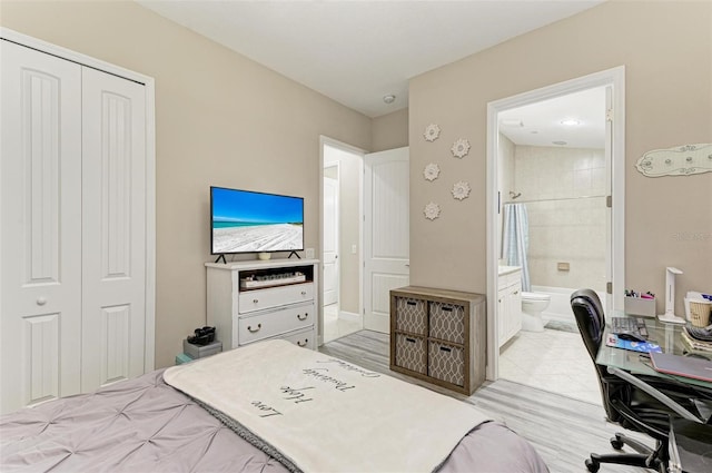 bedroom featuring a closet, ensuite bath, and light hardwood / wood-style flooring