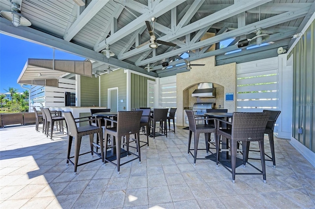 view of patio / terrace with ceiling fan, an outdoor fireplace, and an outdoor bar