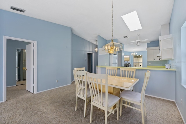 carpeted dining area with vaulted ceiling with skylight and ceiling fan