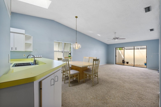 dining room with a wealth of natural light, sink, ceiling fan, and vaulted ceiling with skylight