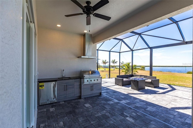 view of patio / terrace featuring an outdoor kitchen, a water view, a sink, grilling area, and an outdoor living space with a fire pit