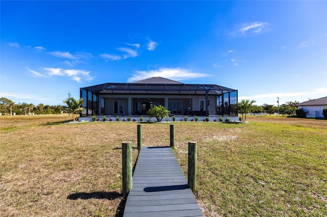 rear view of property featuring glass enclosure and a lawn