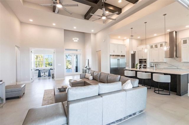 living area featuring baseboards, coffered ceiling, a towering ceiling, ceiling fan, and recessed lighting