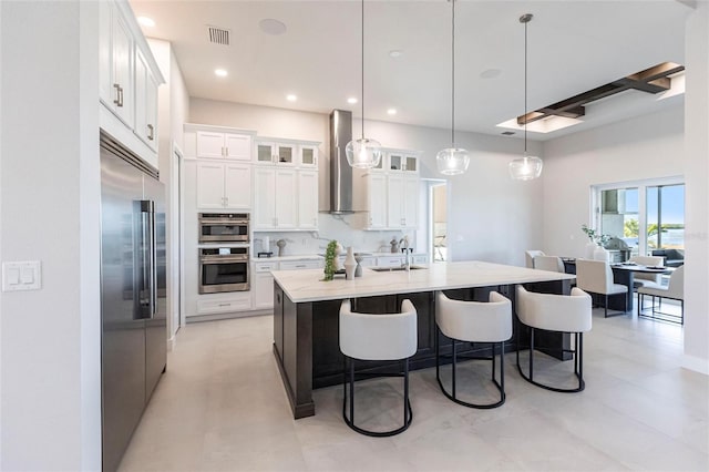 kitchen with a breakfast bar, stainless steel appliances, tasteful backsplash, visible vents, and wall chimney exhaust hood