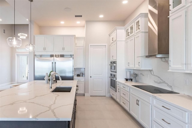 kitchen with visible vents, wall chimney exhaust hood, stainless steel appliances, white cabinetry, and a sink