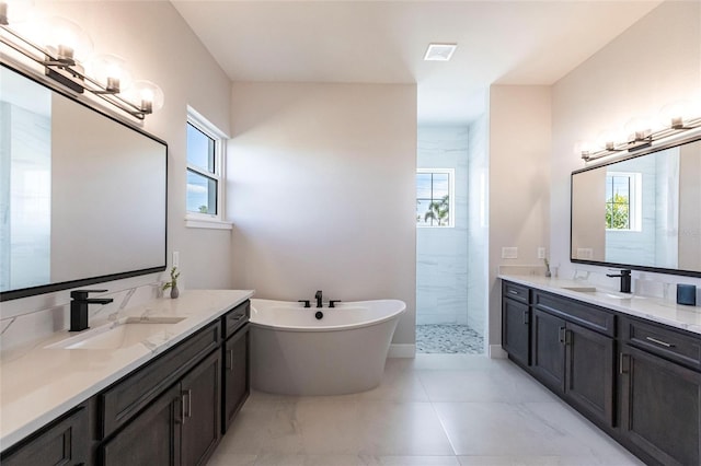 full bath featuring tiled shower, a sink, and a healthy amount of sunlight