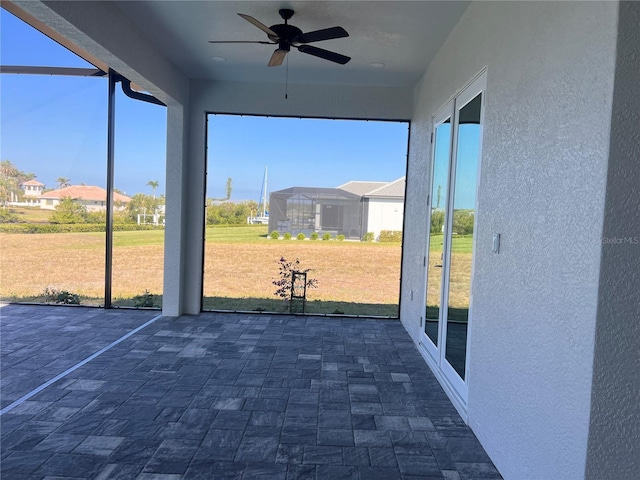 unfurnished sunroom featuring a ceiling fan