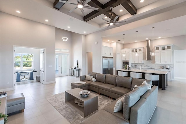 living area featuring beam ceiling, coffered ceiling, a towering ceiling, and baseboards