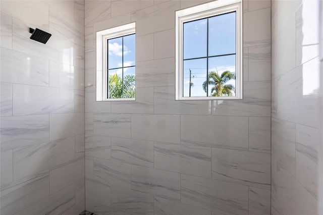 bathroom with a healthy amount of sunlight and tiled shower