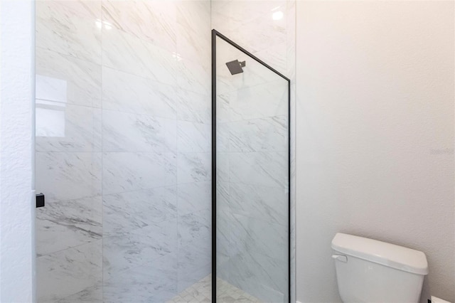 bathroom featuring toilet and a marble finish shower