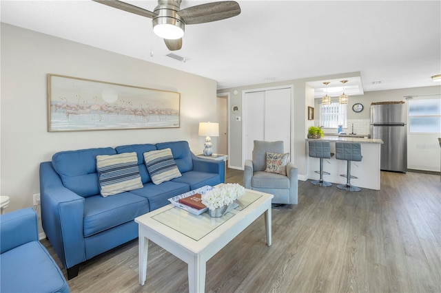 living room featuring hardwood / wood-style floors, ceiling fan, and sink