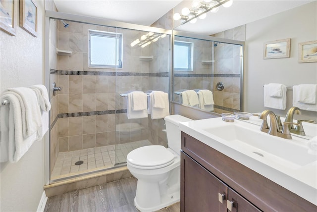 bathroom with toilet, a healthy amount of sunlight, an enclosed shower, and hardwood / wood-style flooring