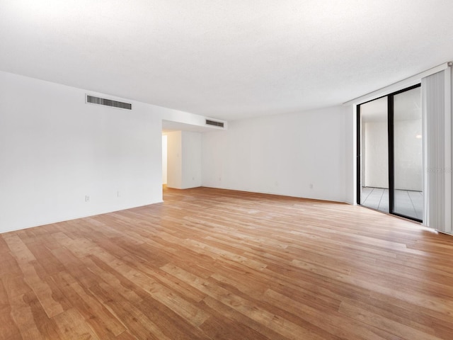 spare room featuring light hardwood / wood-style floors and a textured ceiling