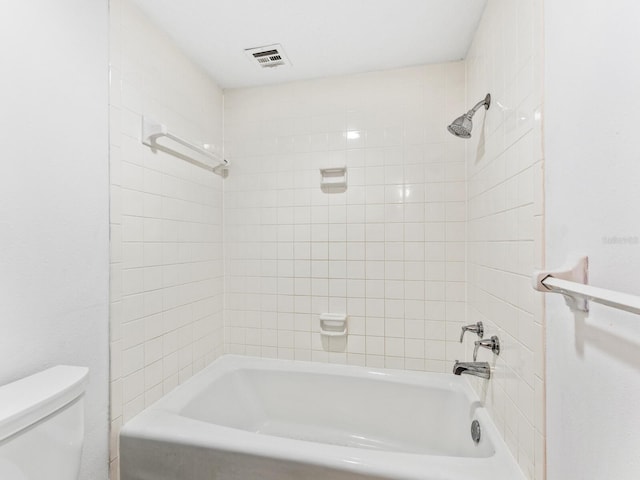 bathroom with tiled shower / bath combo and toilet