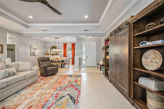 tiled living room featuring crown molding, a tray ceiling, and a barn door