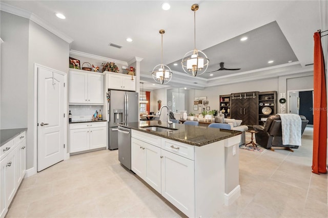 kitchen with appliances with stainless steel finishes, decorative light fixtures, sink, dark stone counters, and a center island with sink