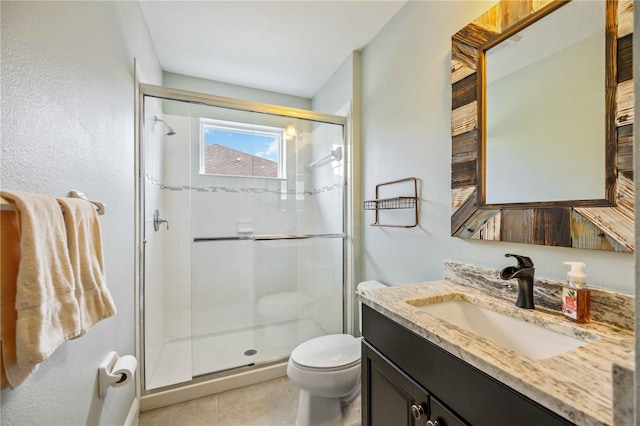 bathroom with a shower with door, vanity, tile patterned flooring, and toilet