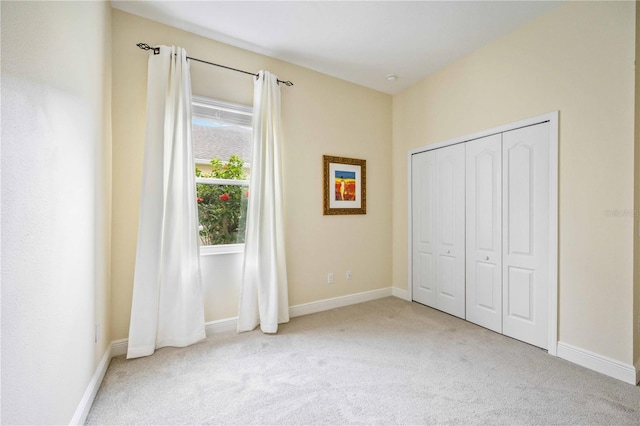 unfurnished bedroom with light colored carpet and a closet