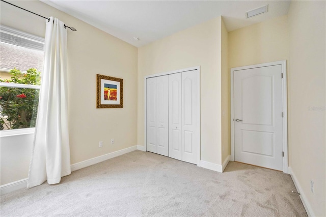 unfurnished bedroom featuring light carpet and a closet