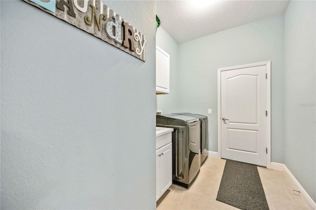 laundry room with cabinets, a textured ceiling, and washing machine and clothes dryer