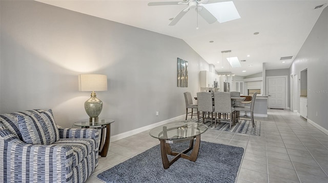 living room with vaulted ceiling with skylight, ceiling fan, and light tile floors