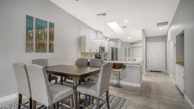 dining space with lofted ceiling with skylight and light tile floors