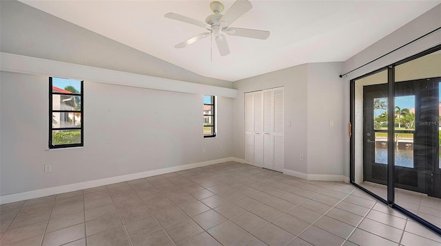 empty room with light tile floors, vaulted ceiling, and ceiling fan