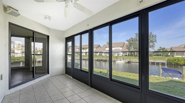 unfurnished sunroom with a water view and ceiling fan