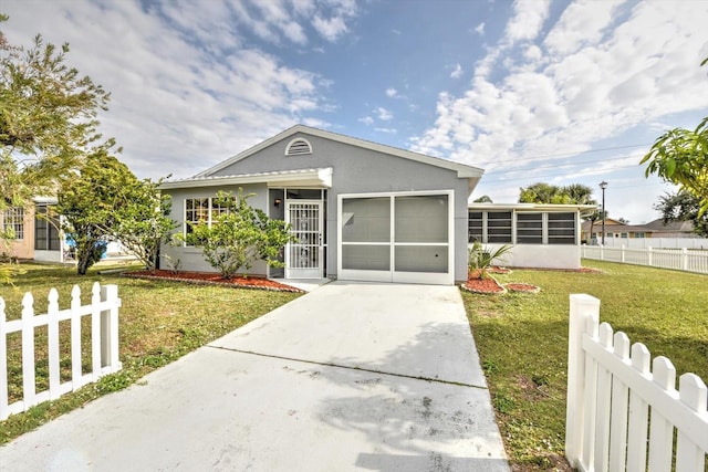 view of front of property featuring a sunroom, a garage, and a front yard