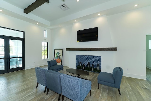 living room featuring beamed ceiling, hardwood / wood-style floors, and french doors