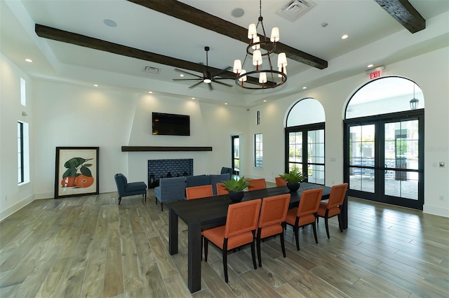 dining room with a tile fireplace, hardwood / wood-style floors, beamed ceiling, and french doors