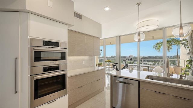 kitchen featuring pendant lighting, light tile patterned flooring, sink, and appliances with stainless steel finishes