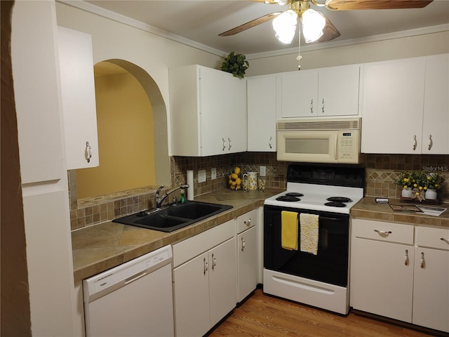 kitchen with white appliances, sink, backsplash, white cabinetry, and ceiling fan