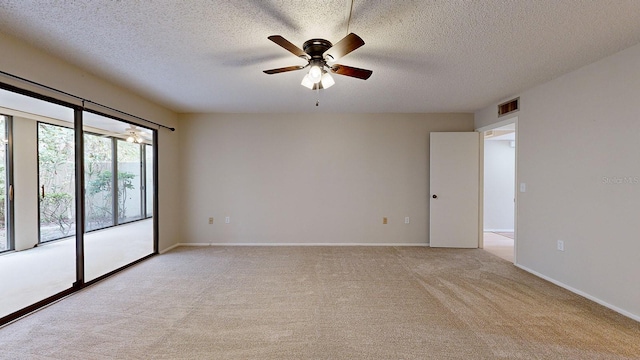 spare room with a textured ceiling, light colored carpet, and ceiling fan