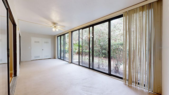 carpeted spare room with ceiling fan and plenty of natural light