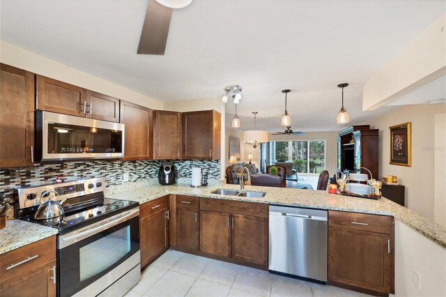 kitchen with stainless steel appliances, sink, kitchen peninsula, ceiling fan, and tasteful backsplash