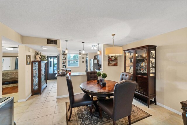 dining space with a textured ceiling and light tile patterned floors